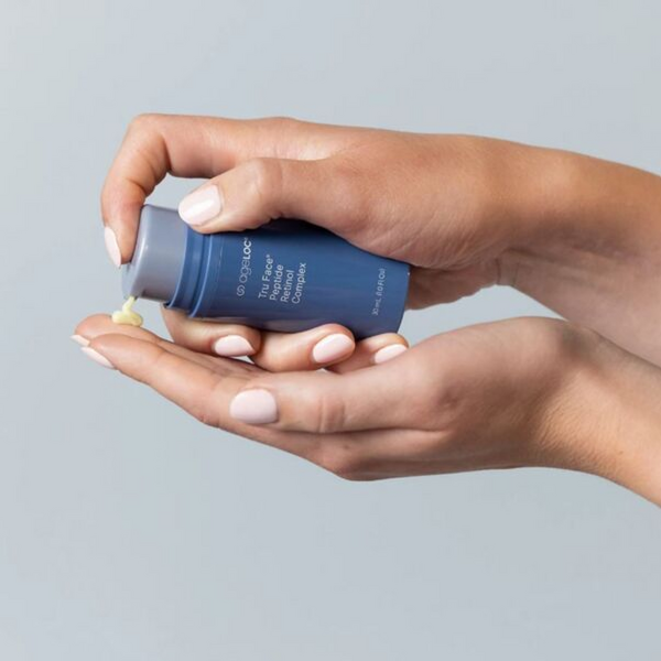 A close-up of a woman’s hands dispensing a texture of ageLOC Tru Face Peptide Retinol Complex onto her finger.