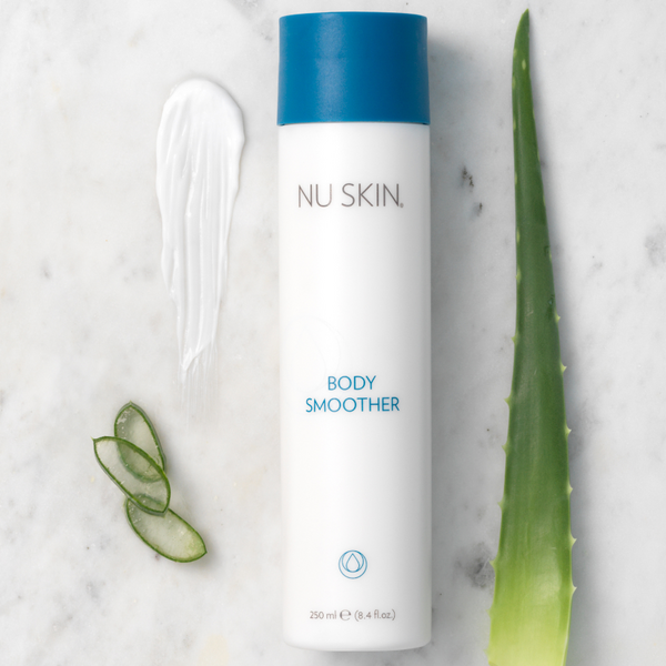 A bottle of the Body Smoother laying on a white background next to a aloe leaf, moist of the product and three slices of aloe.