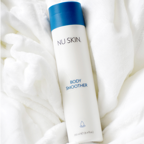 A bottle of the Nu Skin Body Smoother laying down on a white towel. 