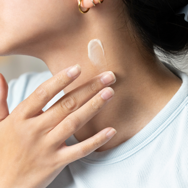 A close-up of a woman applying ageLOC Tru Face Peptide Retinol Complex onto her neck.